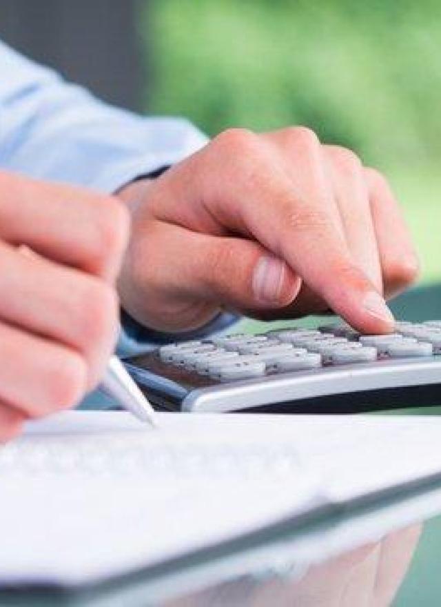 Person using a calculator and writing in a notebook