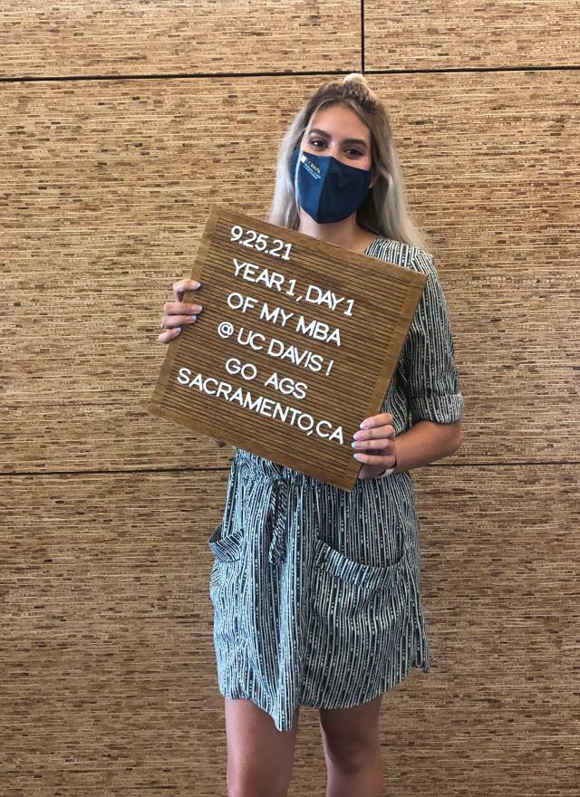 Leticia Garay MBA 24 holds a sign recognizing her first day of grad school