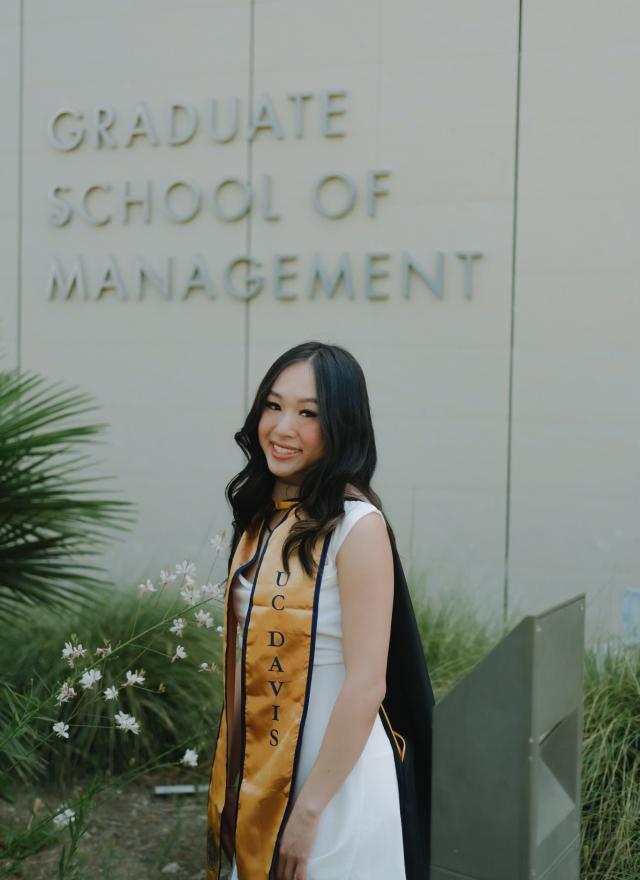 Diana Tran wearing a graduation stole, standing in front of Gallagher Hall