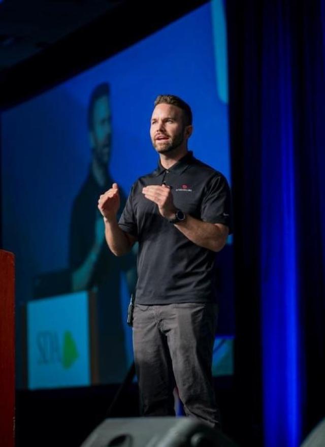 Mac Clemmens speaking on stage, behind a podium