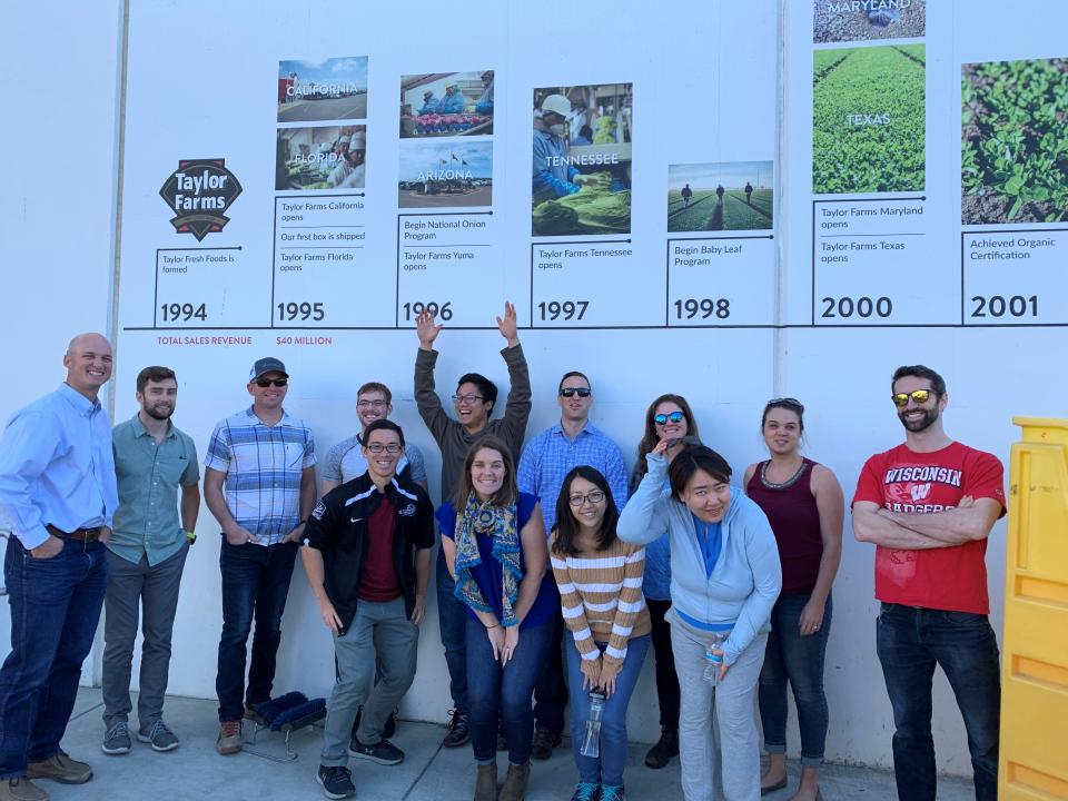Students touring Taylor Fame facilities and standing by a timeline that lists the farm's history
