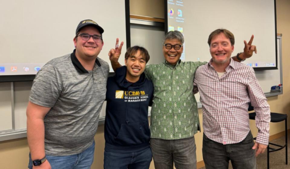 Timothy O'Brien, Alex Schultz, and Kyle Wong, and Lecturer Marc Lowe in a classroom