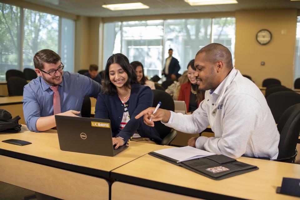 Students sitting and looking at a laptop in a classroom setting